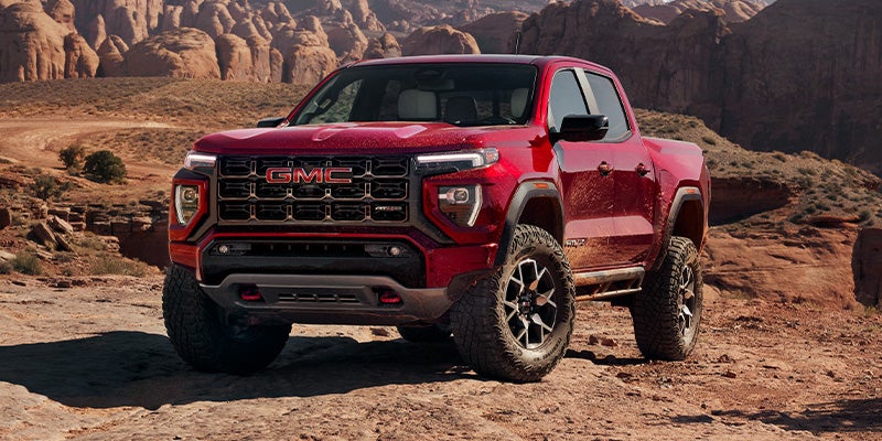 Red 2024 GMC Canyon driving up a small hill