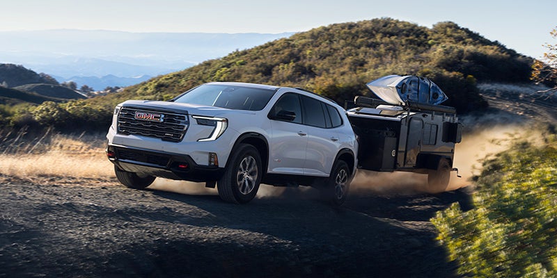 White 2025 GMC Acadia pulling a small trailer